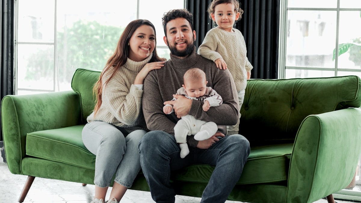 a family sitting on a green couch in a living room
